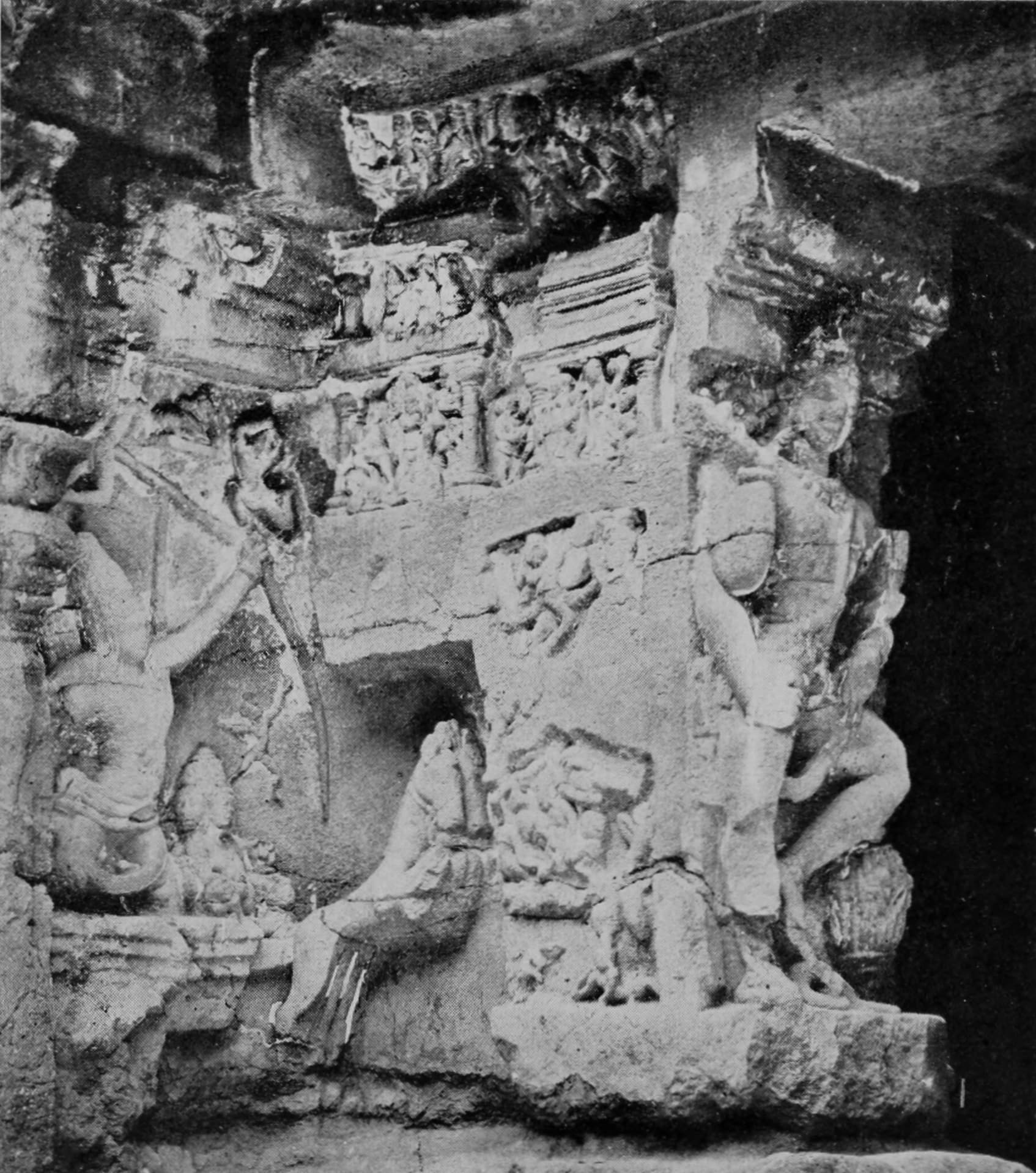 Halftone plate from 1920 showing a rock-cut relief at Kailāsa Temple, Ellora. At the left a figure draws a long bow, the stave running diagonally across the panel, with a chariot form below; carved friezes of small figures run above, and attendant figures stand at the right.